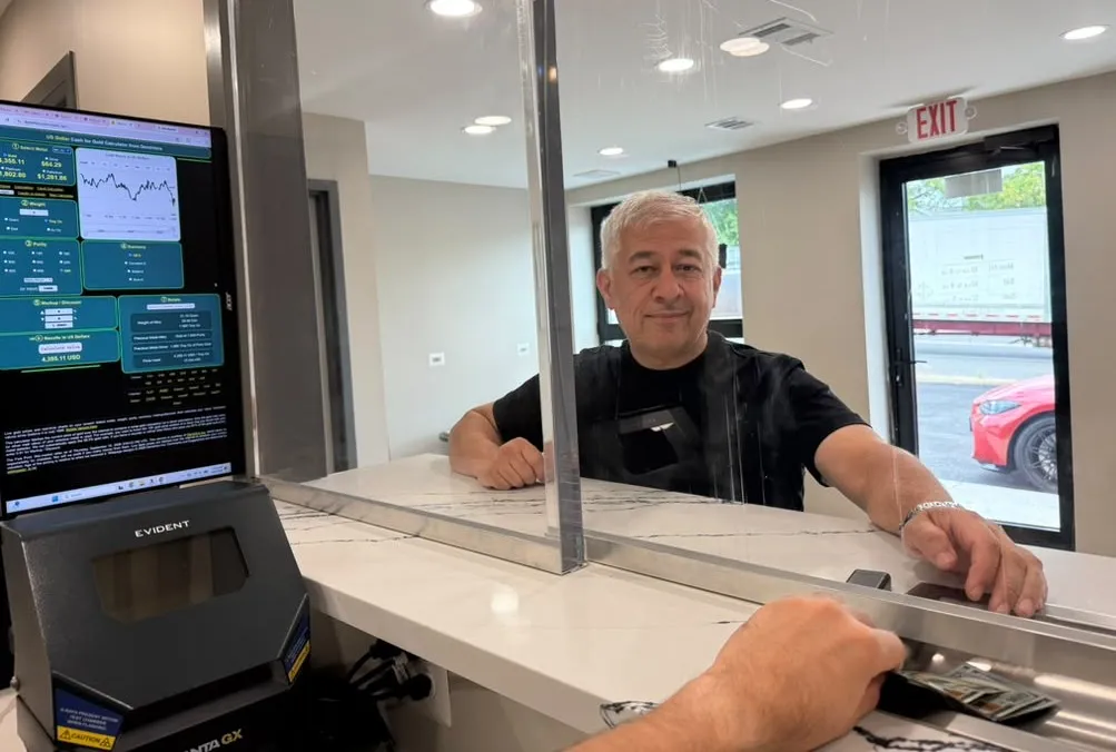 The owner behind the glass counter, with the live price calculator on the screen beside him